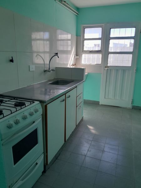 Cocina con mesada de acero, cocina a gas y puerta al exterior